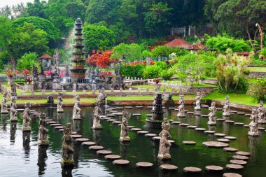 Bali Adası, Endonezya - 10 Ocak 2015: Çeşmeleri, doğal havuzları, balık havuzunda dans eden kadınların geleneksel kostümlü heykelleri olan Antik su sarayı Tirta Gangga. Kültür, Bali Sanatları, Endonezya 'da popüler seyahat merkezi.
