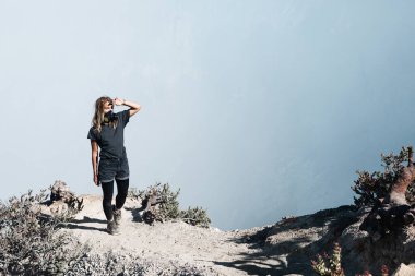 Genç bir kadın, aktif volkan Kawah Ijen 'in zirvesinde, krater asidi gölü üzerinde zehirli dumanla korunuyor. Popüler seyahat merkezi, aile gezisi Bali, Java, Endonezya