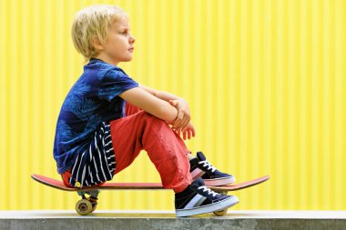 Kaykaylı küçük kaykaycı, kaykay parkındaki çocuk eğitiminden önce iyi eğlenceler. Aktif aile hayatı, yaz tatillerinde açık hava aktiviteleri. Çocuk sporları ve şehir modası.