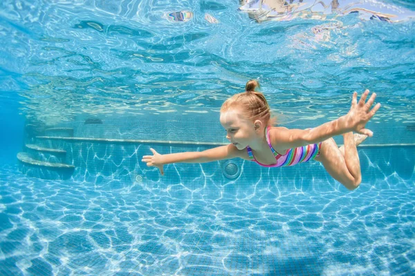 Funny portrait of child learning swimming, dive in blue pool with fun - jumping deep down underwater with splashes. Healthy family lifestyle, kids water sports activity, swimming lesson with parents.