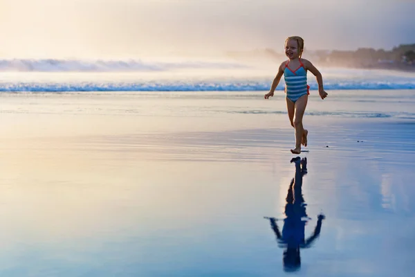 幸せな家族は熱帯の海のビーチリゾートで楽しんでいます 面白い赤ちゃんの女の子は波の端に沿ってウォータープールでスプラッシュで実行されます アクティブな子供のライフスタイル 子供と一緒に夏休みに水泳活動をする人々 — ストック写真