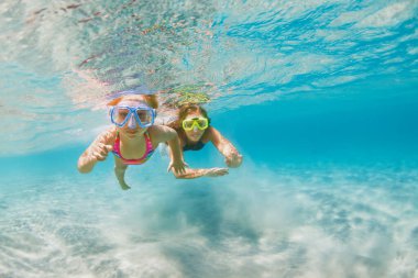 Su altı dünyasını keşfetmek için mercan resiflerinde dalış yapan maske takan çocuklu genç bir anne. Yaz macera kampında aile seyahati yaşam tarzı. Çocuklarla plaj tatilinde yüzme aktiviteleri.