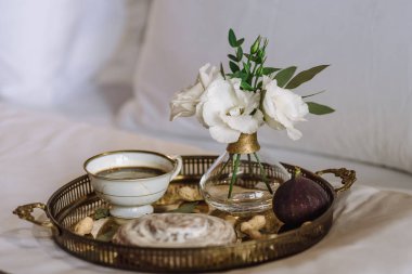 bir tepsi kurabiye ve bir fincan kahve, bir vazonun yanında