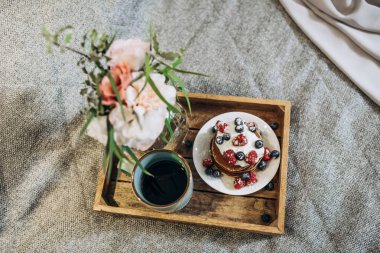 Kahve, çiçekler ve yatakta böğürtlenli krep. Geline yatakta kahvaltı. yumuşak odak