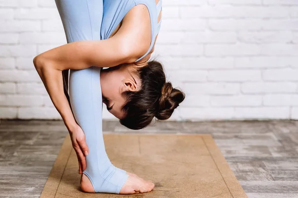 Ung yogi kvinna praktiserar yoga koncept. flicka klädd i blå sportkläder gör pilates motion på mattan — Stockfoto