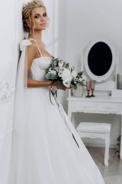 Güzel saç stili olan gelin. Beyaz iç çamaşırlı, gelinlikli model sarışın.