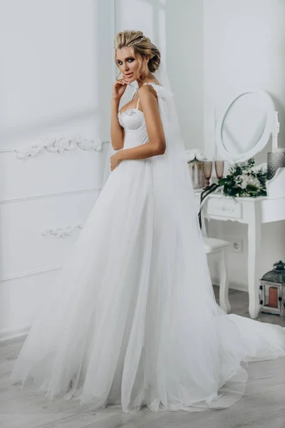 Невеста с красивой прической. Модель блондинка в свадебном платье в белом интерьере — стоковое фото