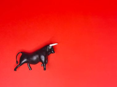 Kırmızı arka planda siyah bir boğa figürünün yakın çekimi. Profilde bir boğa, beyaz boynuzlar. Bull ileriye bakıyor. 2021 Çin yıldız falı sembolü.. 