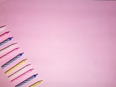 Pembe arka planda çok renkli doğum günü mumları. Doğum günü ya da yıldönümü kartı ya da davetiye arkaplanı. Metin ve tasarım için boş alanı olan stok fotoğrafı.