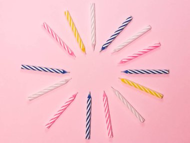 Pembe arka planda çok renkli doğum günü mumları. Tebrik kartı için boşluk, doğum günü davetiyesi için geçmiş, bayram ve partinin sembolü..
