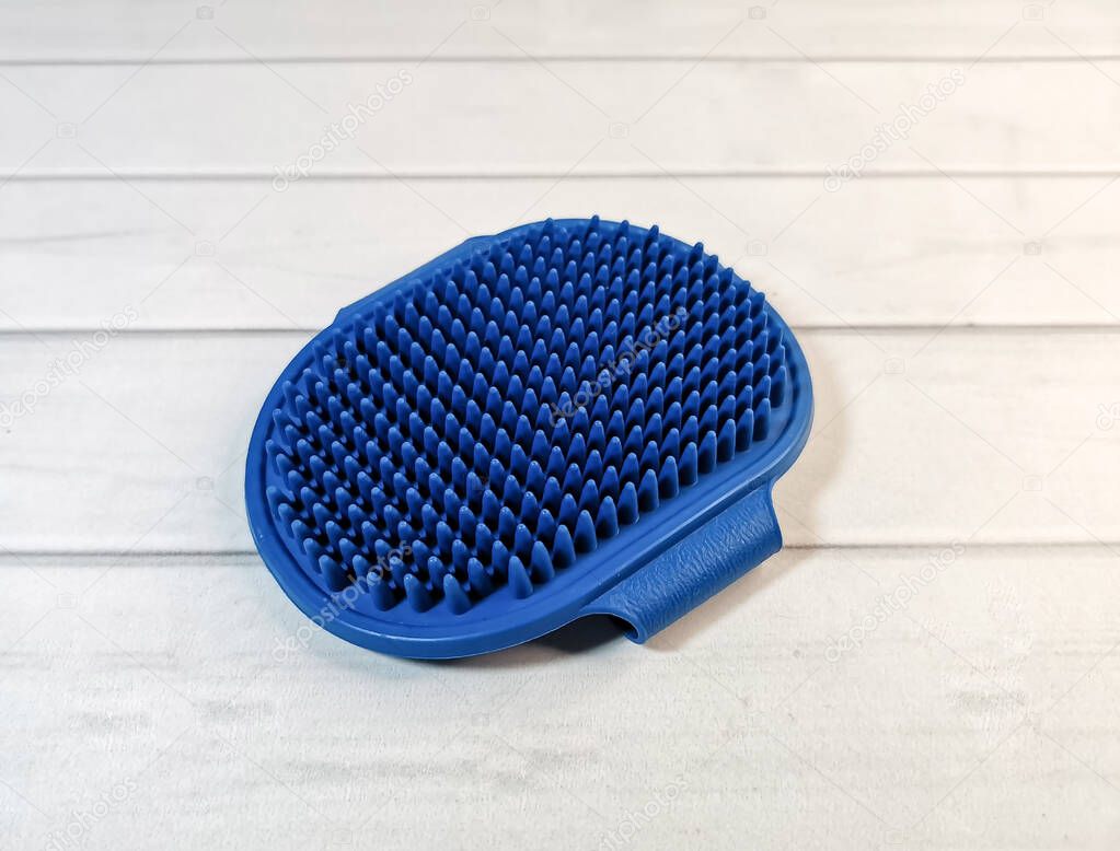 Soft blue rubber massage brush for animals. Pet care accessories. Hand-held massage brush to remove excess hair from dogs and cats during molting.