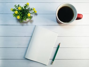 Yazmak için en iyi iş yeri manzarası. Masanın üzerinde bir kalem, bir fincan sade kahve ve bir ev bitkisi olan bir defter var. Sabah, fikir üretmek için en iyi zamandır. İlham için rahat bir atmosfer.