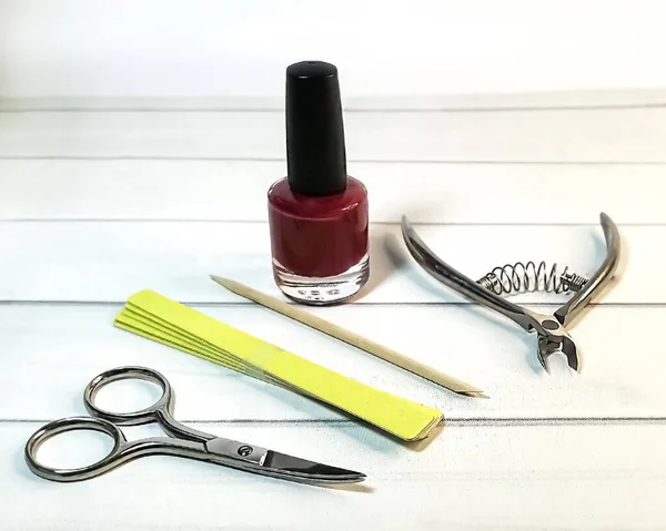 Set for self-care of nails: manicure scissors and tweezers, a cuticle stick, nail polish and a set of files. The concept of home personal care without visiting a beauty salon. Space for text or logo.