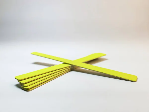 Set of yellow disposable nail files on a gray gradient background. Tools for independent manicure and pedicure, nail care. Space for your text or logo. Selective focus.