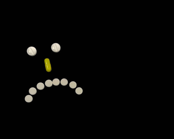 Sad smile made of pills on a black background. The concept of a bad diagnosis, depression, illness. Space for text or logo
