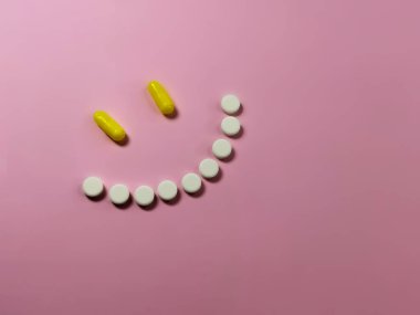 Pembe arka planda haplardan yapılmış gülümseme. İyileşme konsepti, depresyonun üstesinden gelme, sağlık. Ağrısız tedavi. Mesaj veya logo için boşluk. Yumuşak seçici odak