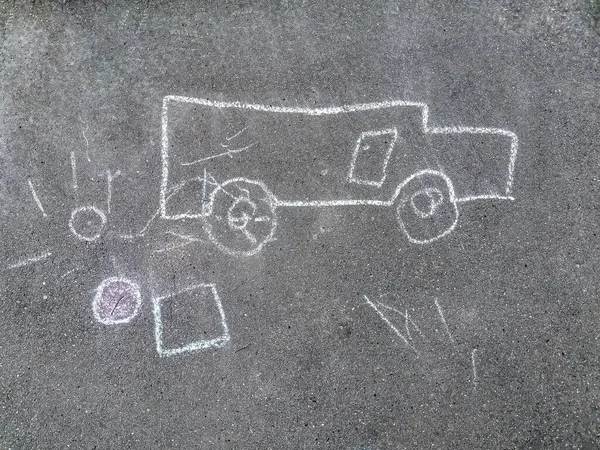 Children\'s drawing with chalk on the pavement. The child painted a white chalk car and the sun on the sidewalk. Concept: childhood, creativity, walks.