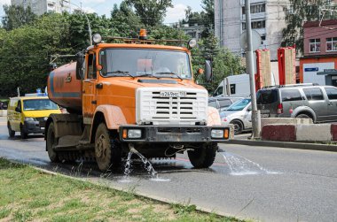 Moskova, Rusya - 12.07.2020 Şehir Su Sulama Makinesi dar bir caddede bir yaz günü yolu suluyor. Sıcak bir günde kentsel servis yolu sulanıyor.