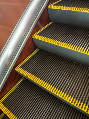 Yürüyen merdiven metroya biner. Yan görüş. Sarı uyarı çizgisi.