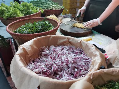 Bir sokak kafe çalışanı pho-bo çorbası yapmak için malzemeleri hazırlar. Vietnam 'da bir kafede zencefil dilimlemek. Büyük sepetlerde, doğranmış kırmızı soğan ve otlarla. Geleneksel Asya yemekleri.