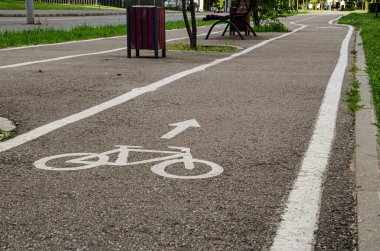 Yol boyunca boş bisiklet yolu var. Ön planda, asfaltta 