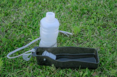 Yeşil çimenlikteki kedi ve köpek için taşınabilir su şişesi. Evcil hayvan su dağıtıcısı. Evcil hayvanlar için aksesuarlar. Sıcak havada yürürken köpeklerin susuz kalmasını önlemek için..