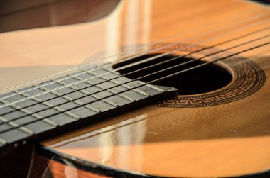 Güneş ışığında gitar tellerine yakın çekim. Gitar fretboard kısmı, akustik altı telli tahta gitar, telli müzik aleti..