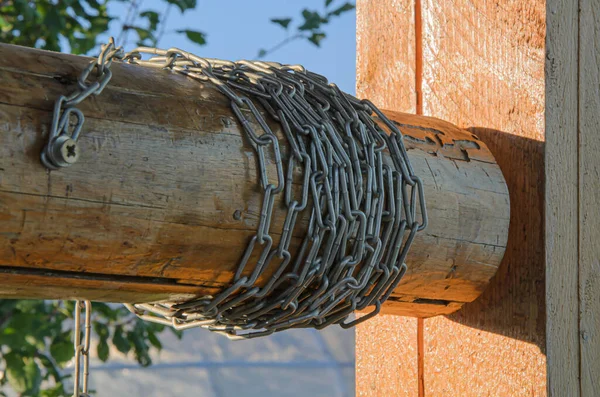 Chain is on a hand-operated wooden well. Life outside the city, village life, outdated water extraction technologies.