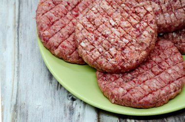 Tabakta taze çiğ et köftesi ve ahşap masa. Barbekü hazırlığı, sığır eti ürünleri, geleneksel et yemeği.