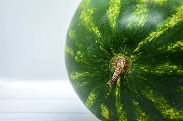 Kabuğu soyulmamış yeşil çizgili karpuz ve sapına yakın çekim. Bir karpuzun olgunluğunun seyyar amcasının durumuna göre belirlenmesi. Metin için boşluk