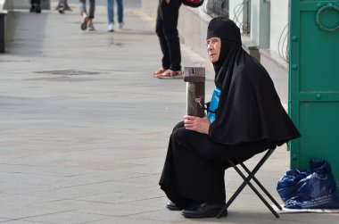 Siyah cüppeli yaşlı bir rahibe, şehir kilisesinin kapısındaki ahşap bir kutuda bağış topluyor. Dini kuruluşlara nakit bağışlar. Moskova / Rusya - 09.06.2020