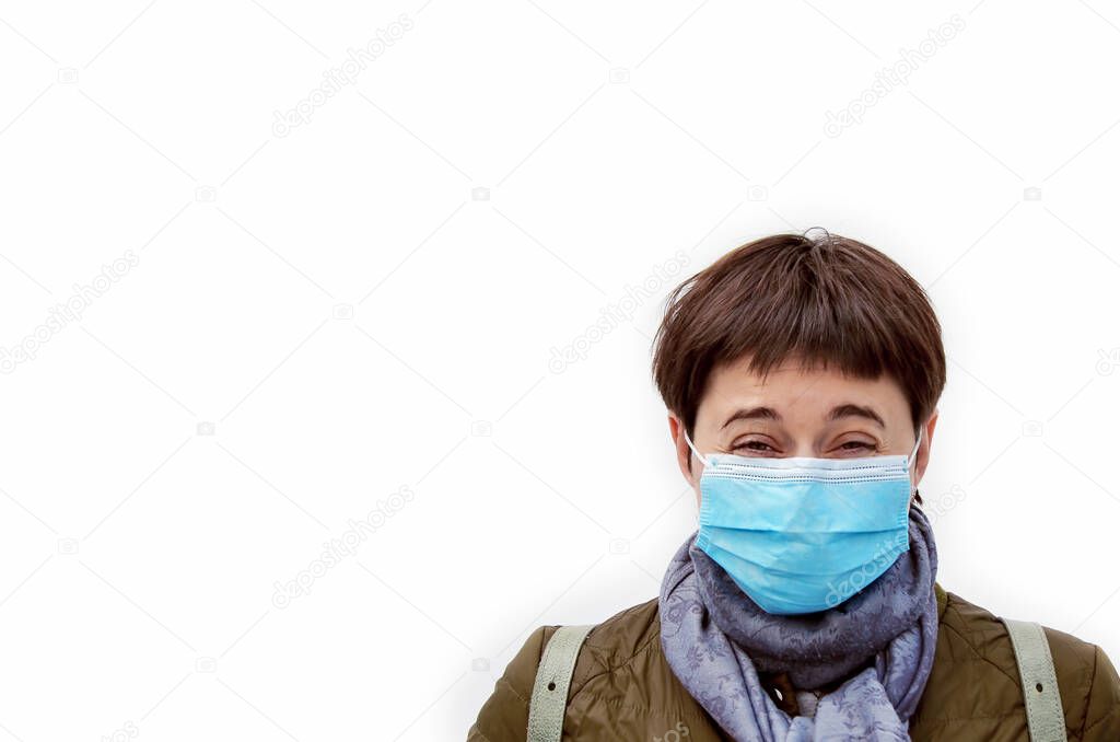 Young brunette woman laughing with disposable blue medical mask on fase. Laughter conquers disease. White background. Protection from virus, safety measures to health during a pandemic. Spase for text