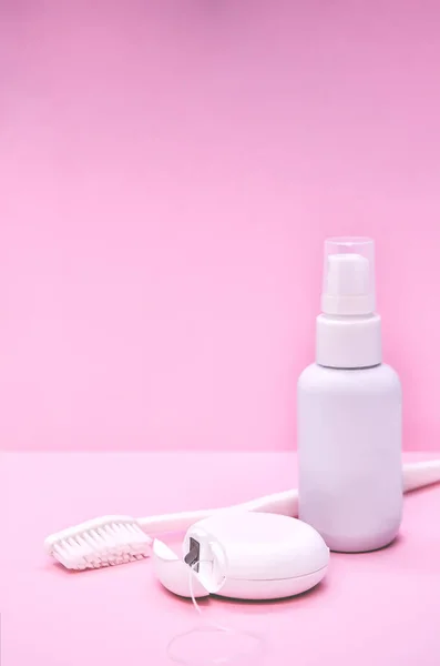 Oral Care: White Toothbrush, Dental Floss and breath freshener on pink background. Vertical image, space for text. Concept: dental services, oral hygiene, dental care.