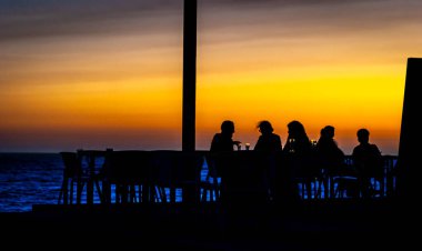 ışıklandırma, gölgeler. Arkadaş grupları gün batımında Porto, Portekiz 'de deniz kenarında birkaç bira içiyorlar..