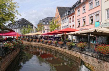 Saarburg, Rheinland-Pfalz / Almanya 24 Ağustos 2018: Saarburg şehir eski değirmenler doğru akan Cityscape tarihi eski şehir bölümü ve Leuk Nehri ile. Bar ve restoran uzun kanal oturan insanlar.