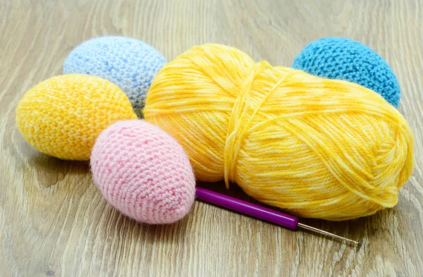 Crochet easter eggs in blue pink yellow on wooden background — Stock Photo, Image