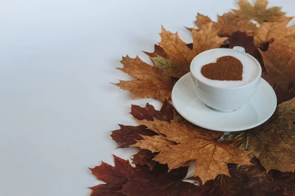 Coffee cup with a pattern in the form of a heart. Cozy leaves and place for your text