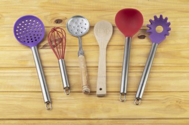 Ahşap masanın üzerinde renkli mutfak aletleri.