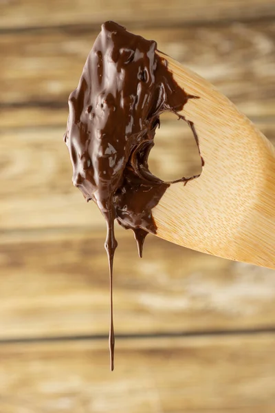 木製のスプーンから落ちる溶かしたチョコレート — ストック写真