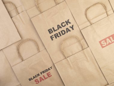 Kara Cuma ve İndirim metniyle kahverengi kağıt alışveriş torbaları.