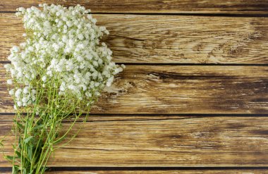 Tahta masanın üzerinde küçük beyaz çiçekler..