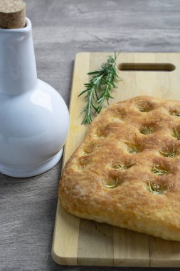 Tahtanın üzerinde seramik zeytinyağı şişesiyle biberiye Focaccia..