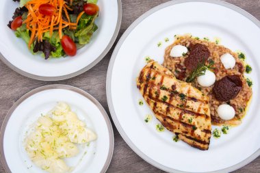 Izgara tavuk, peynir ve domates pilavı, havuç, marul ve dilimlenmiş ananas ahşap masada..