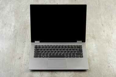 Beton arkaplan üzerinde siyah boş ekran olan dizüstü bilgisayar.