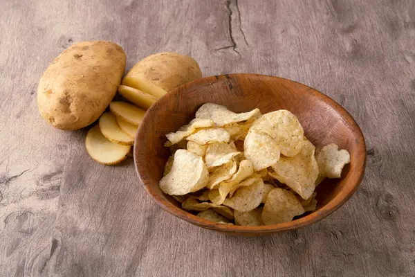 Scheiben Geschnittene Rohe Kartoffeln Und Kartoffelchips Auf Einer Hölzernen Schüssel — Stockfoto