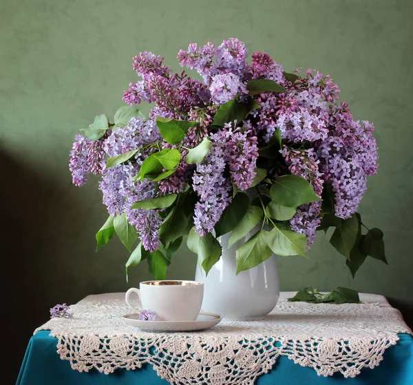 Bouquet of lilac in a vase and a retro Cup. Rustic still life with flowers.