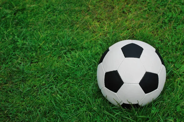 Football black and white ball on the green grass. Empty space for text on the left. Copy space. Soccer ball.
