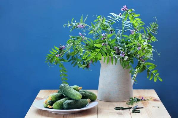 素朴な花束と静物青い背景の上に新鮮なキュウリ 花と野菜 — ストック写真