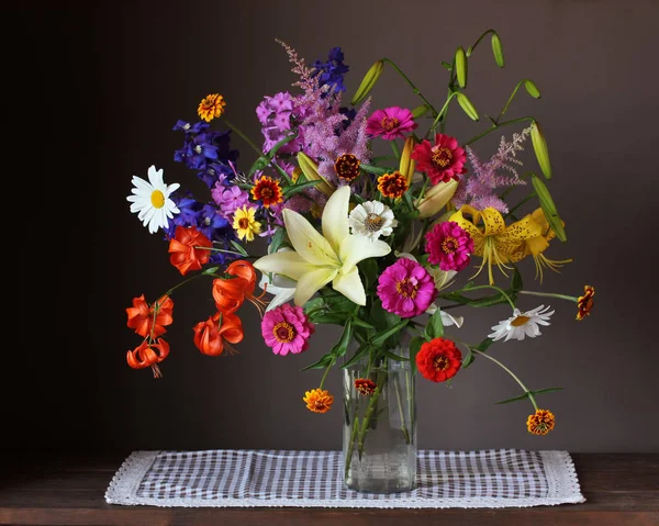 美丽的鲜花花束在一个玻璃花瓶在黑暗的背景 百合和百日草 — 图库照片