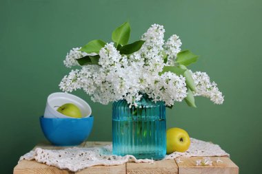 vazo ve sarı elma yeşil bir arka plan üzerinde beyaz leylak buket. ülke natürmort.